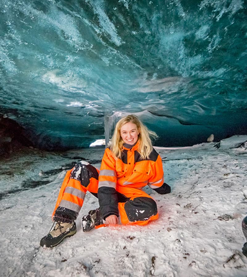 Young lady sitting inside a natural ice cave