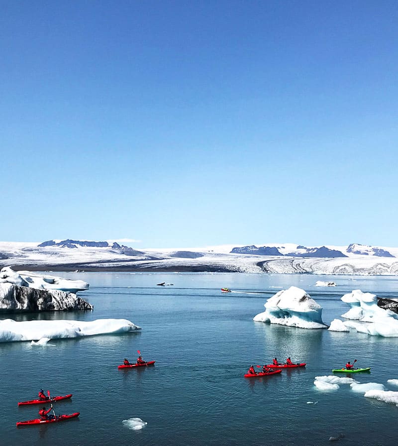 Kayaks on the Glacier Lagoon. Blue water, blue sky and icebergs